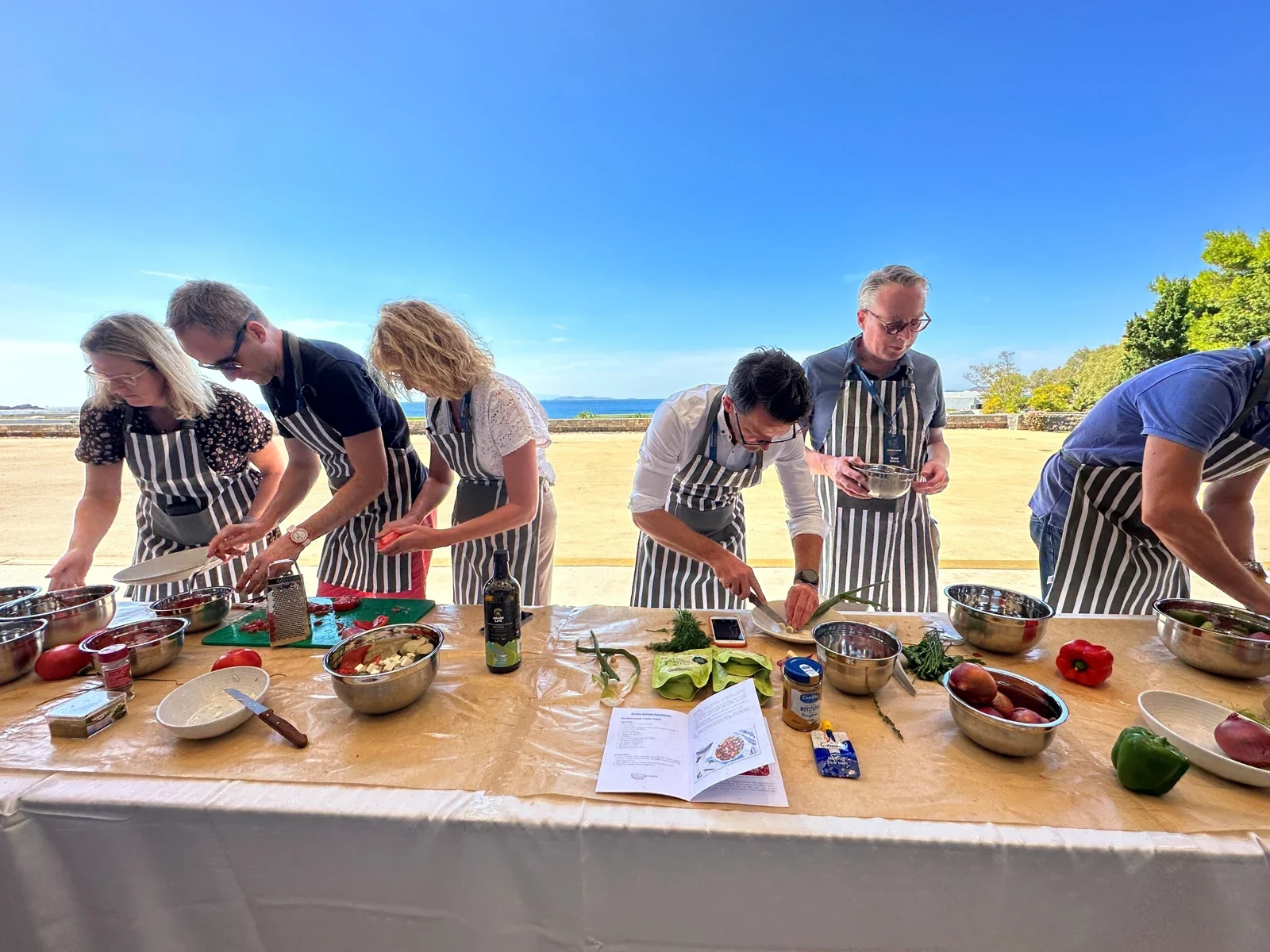 Participants preparing Greek food together outdoors