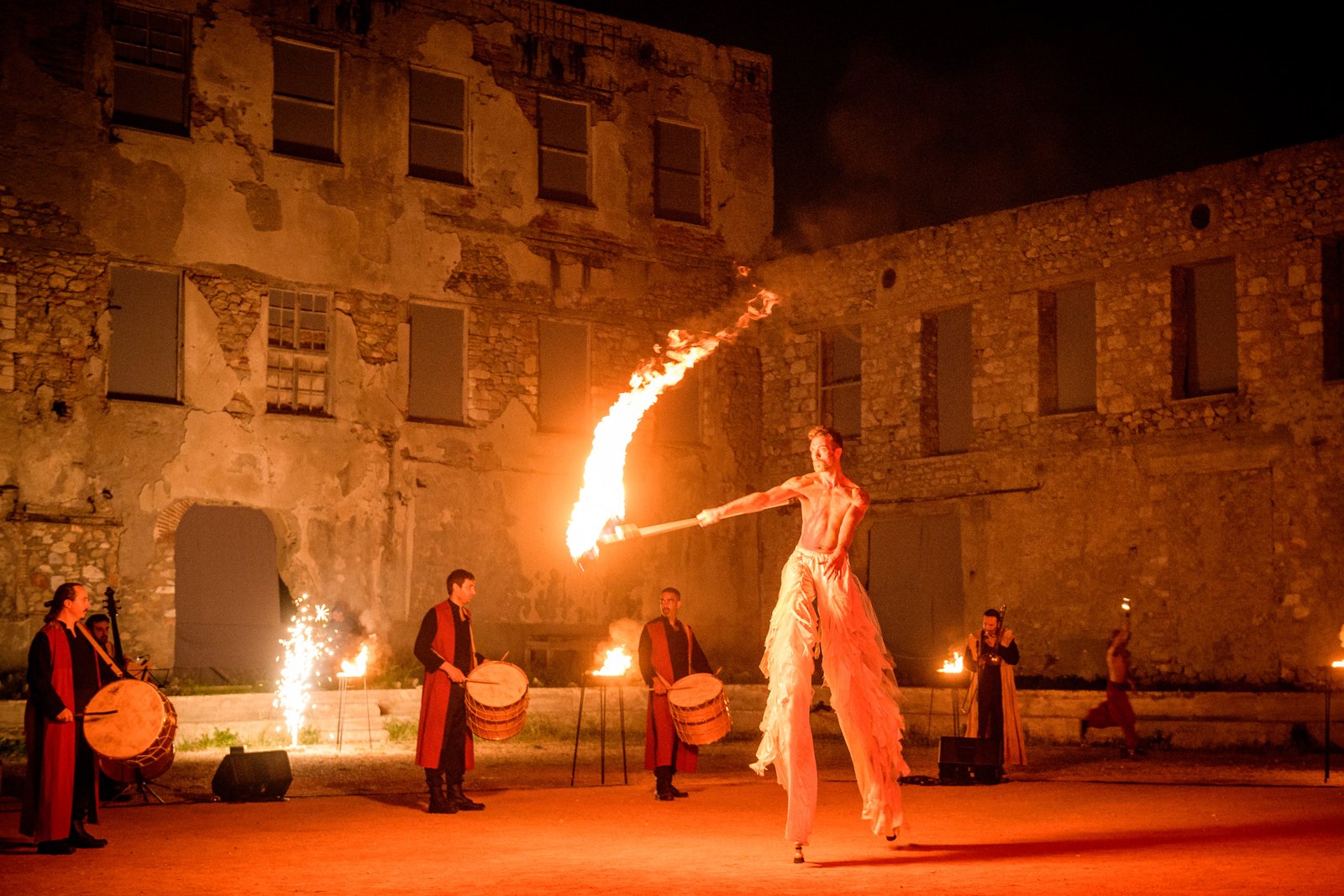 Fire performer in a stone courtyard at night