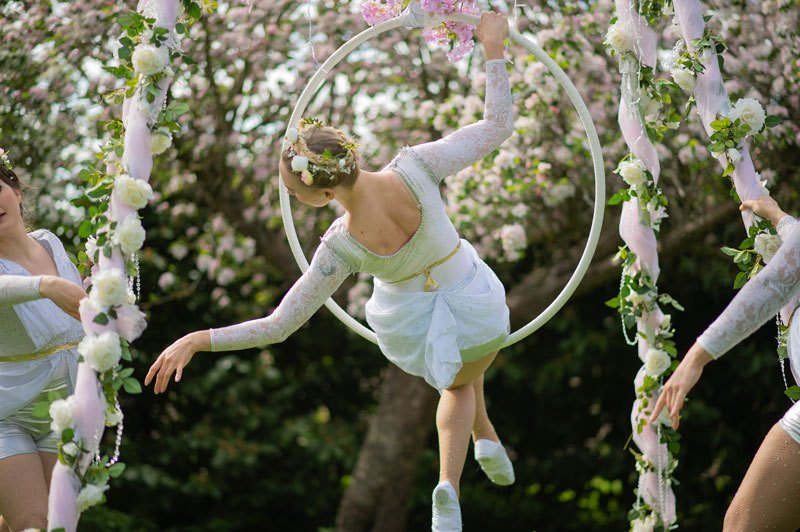 Aerial performer on a floral hoop in a garden