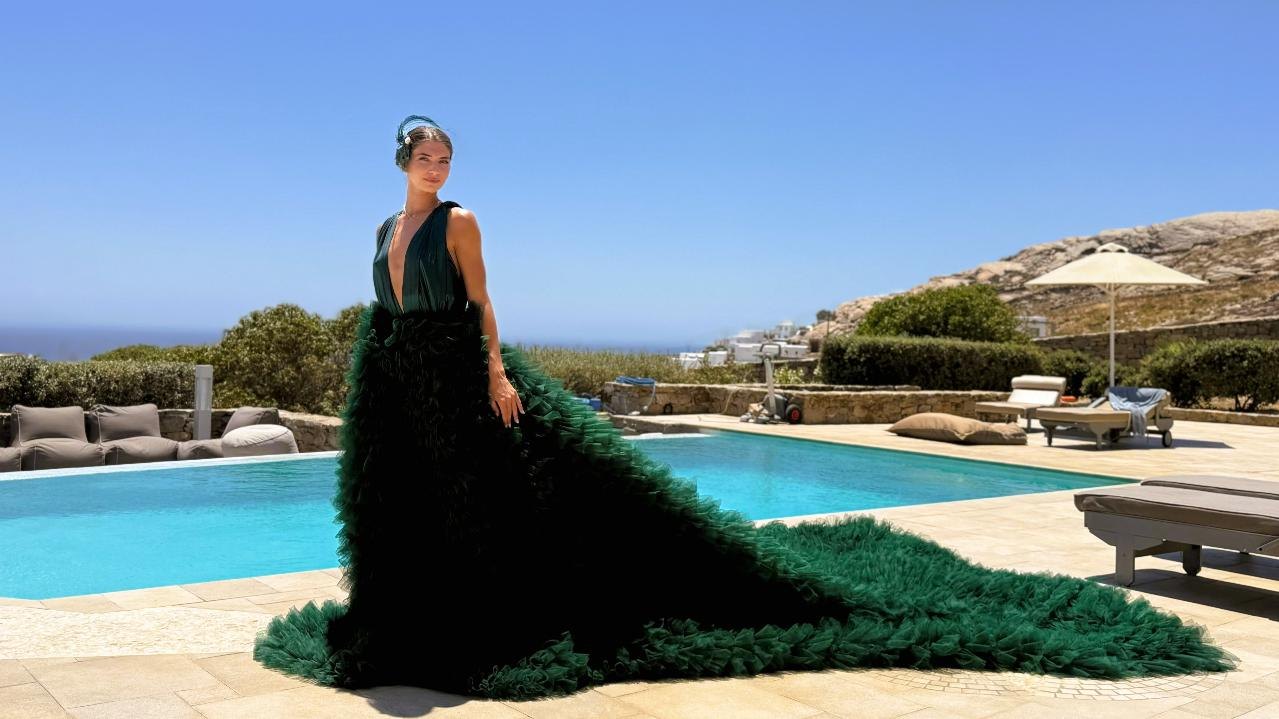 Performer in a long green gown beside a pool