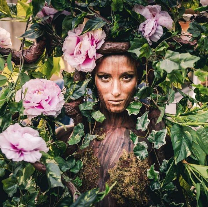 Performer with floral body art and vine-inspired costume