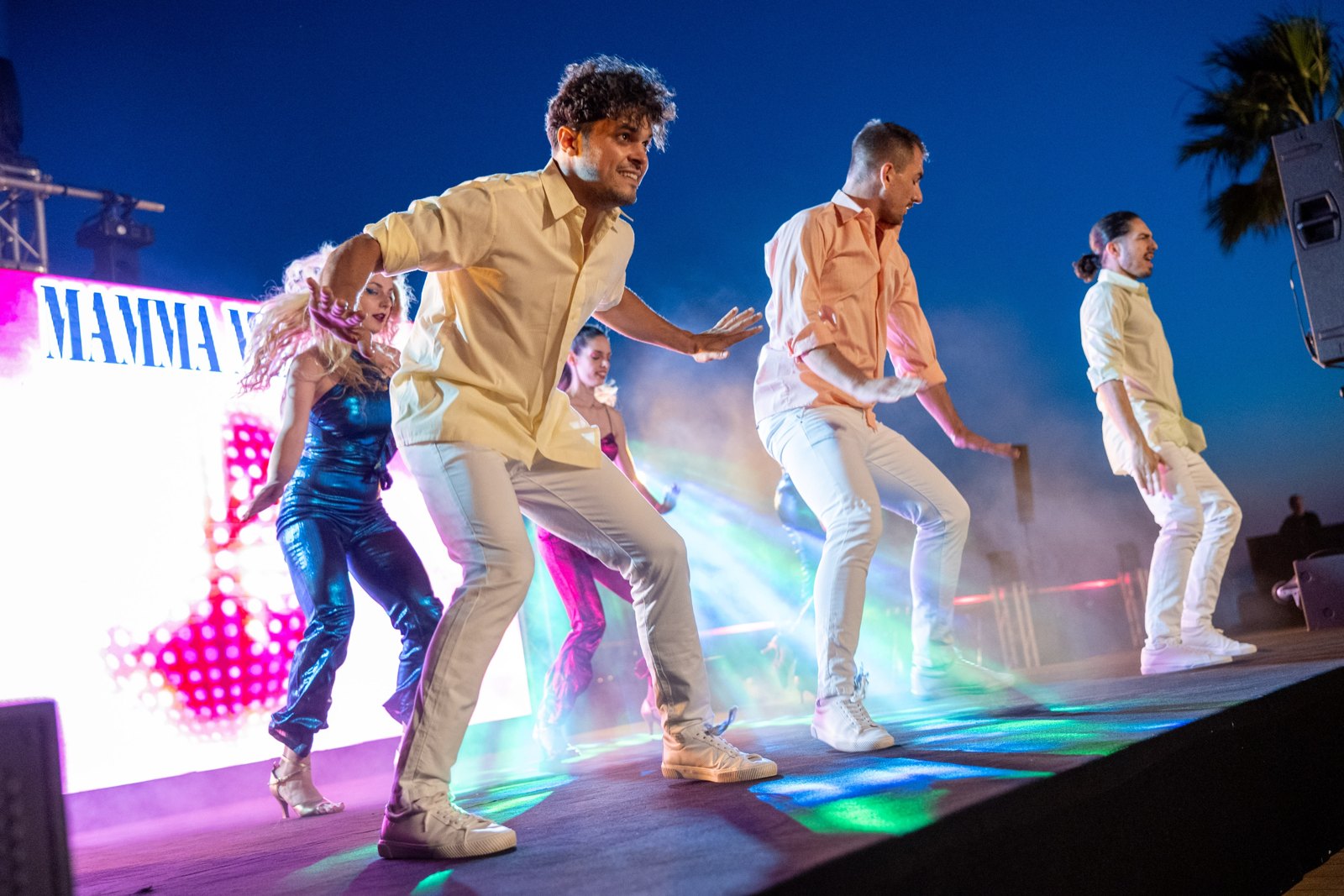 Mamma Mia performers dancing in a stage medley