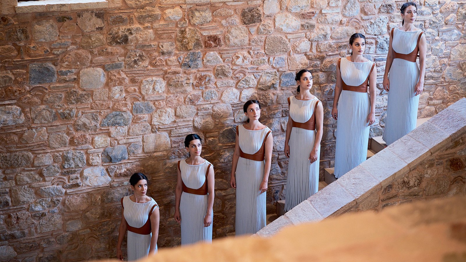 Priestess performers in white dresses on stone steps