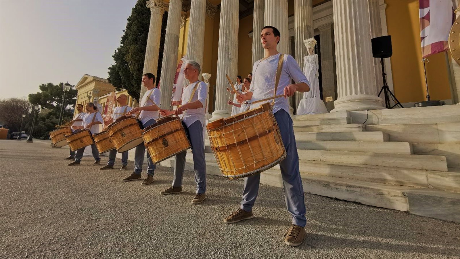 Olympic drummers performing outside a classical building