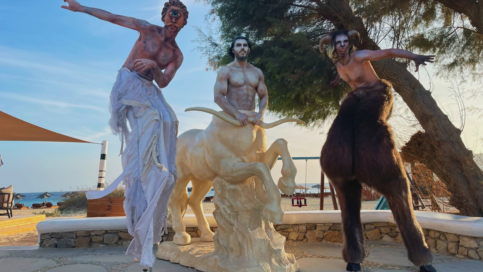 Costumed mythical characters welcoming guests beside the sea