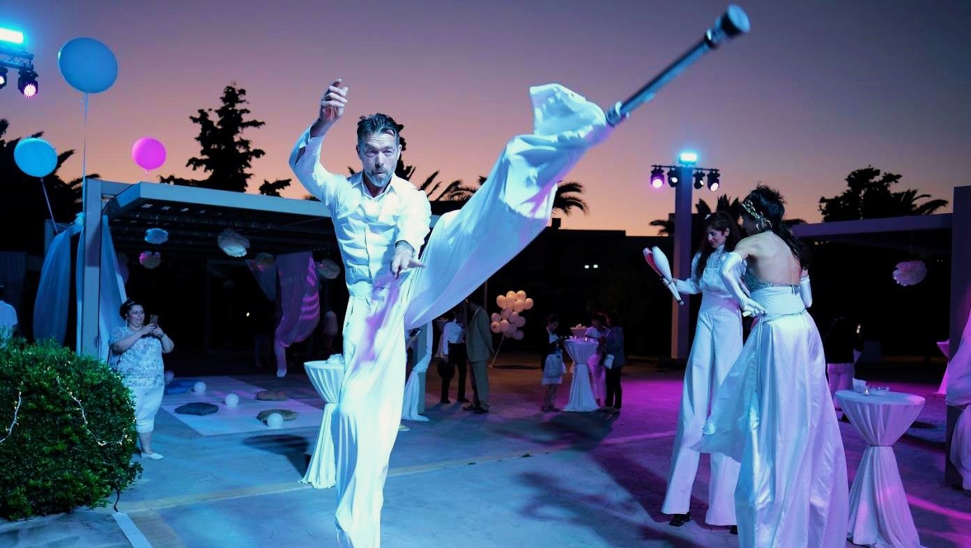 Jugglers in white costumes performing at an evening event