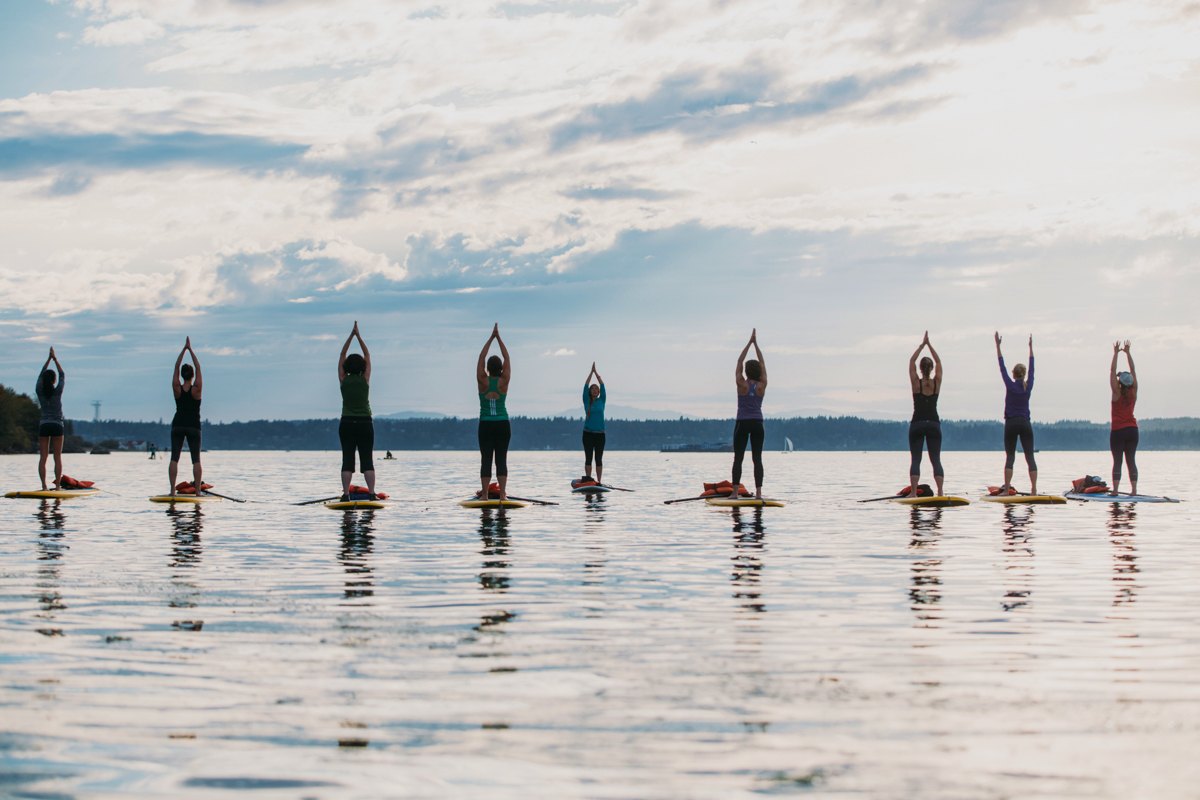 Group practising yoga on stand-up paddleboards